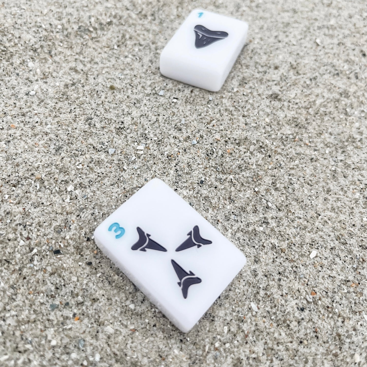 3 Dot and 1 Dot tiles in the sand featuring sharks tooth design